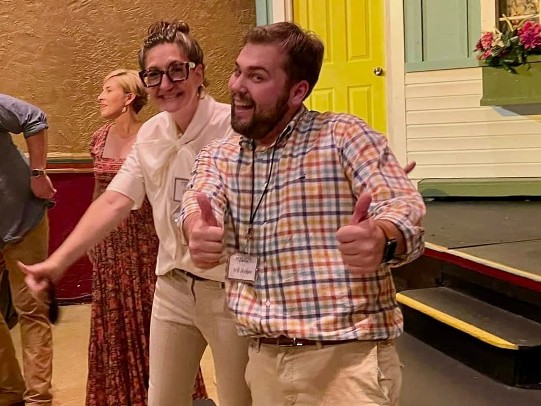 Will Hodges on the Laurel Little Theatre set, smiling broadly and giving two thumbs up in a plaid shirt.